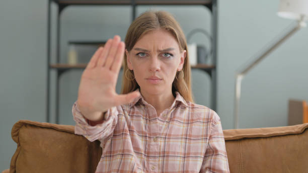 istock Stop Gesture by Young Woman Sitting on Sofa at Home 2194833843