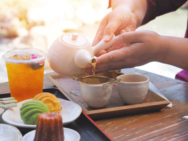 istock Hand holding teapot pouring hot tea through stainer into a cup 2194834094