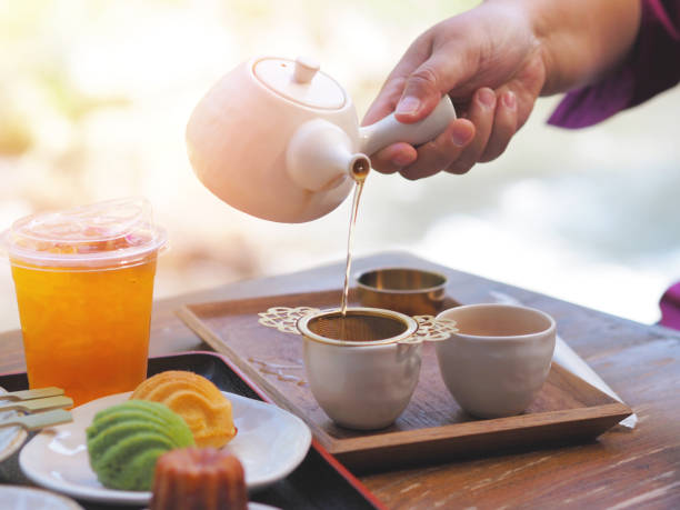 istock Hand holding teapot pouring hot tea through stainer into a cup 2194834120