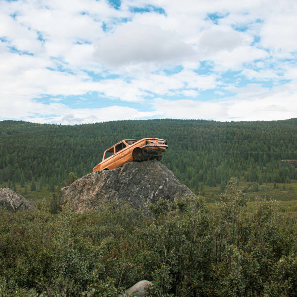 istock an old ancient car, broken down on a mountain road, placed on a large rock as a reminder of road safety 2194838368
