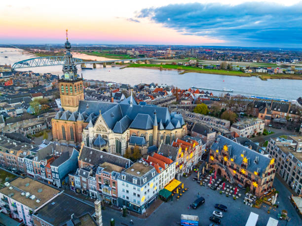 Skyline of the city Nijmegen on the riverbank of the Waal seen from the Grote Markt during sunrise. Various ships are passing the river during this beautiful cold winter morning during the start of the day.