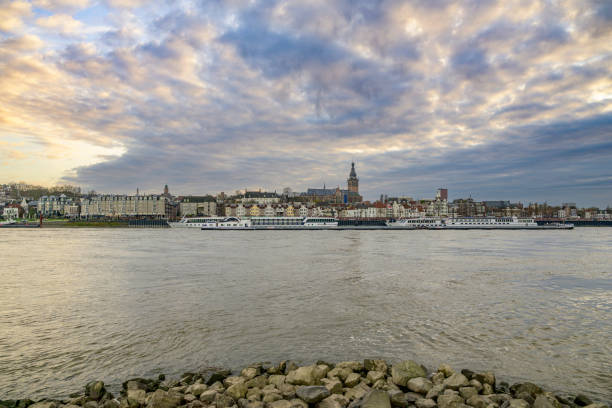 Skyline of the city Nijmegen on the riverbank of the Waal river during sunset. Various ships are passing the river during this beautiful cold winter afternoon.
