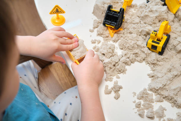istock The child engages in a sensory activity, feeling the soft kinetic sand under their hands. Kid aged three year 2194845687