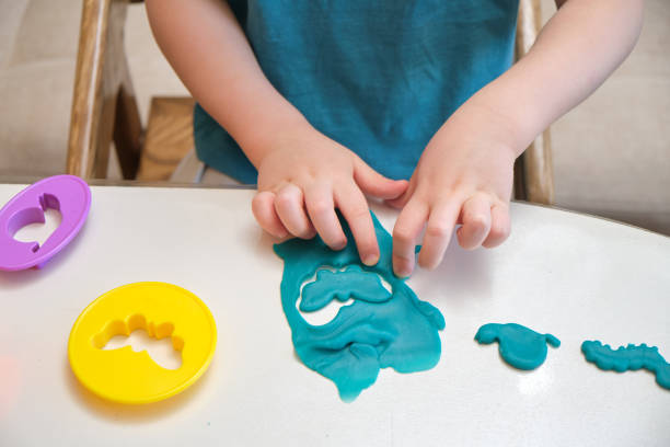 istock The child is shaping a craft project with blue clay during a fun indoor activity. Childhood creativity blossoms as the baby plays with plasticine at the home table. Kid aged three year 2194845978