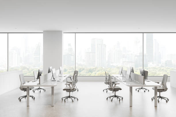 istock Modern open office layout with white desks and chairs, large windows showcasing a cityscape and greenery outside. Bright and minimalistic design. 3D Rendering 2194847180