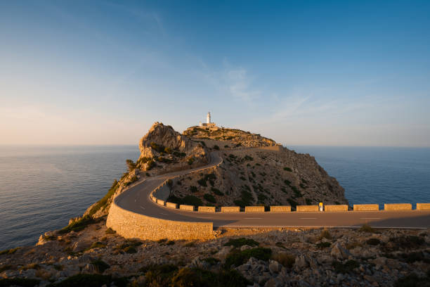 A winding road leads to the coastline bathed in sunset light in Mallorca.