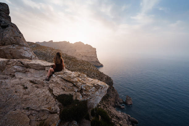 istock A woman sits on a rock, admiring Mallorca’s dramatic cliffside views. 2194848013