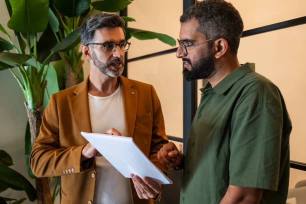 istock Two businessmen in their 30s discussing paperwork with serious expression 2194848382