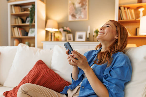 istock Happy woman using mobile phone relaxing on sofa at home 2194857136