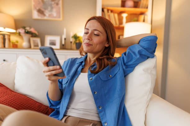 istock Relaxed woman enjoying her smartphone on a comfortable sofa at home 2194857146