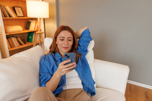 istock Young woman relaxing on sofa using mobile phone at home 2194857678