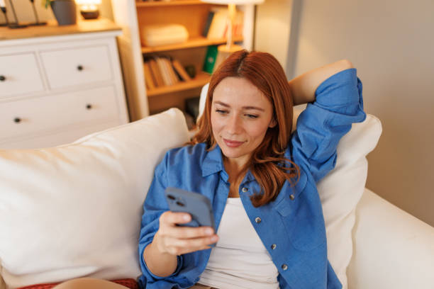 istock Young woman relaxing on sofa using smartphone at home 2194857680
