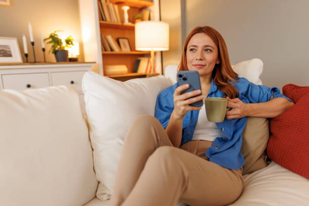 istock Woman relaxing on sofa using smartphone and drinking coffee 2194857783