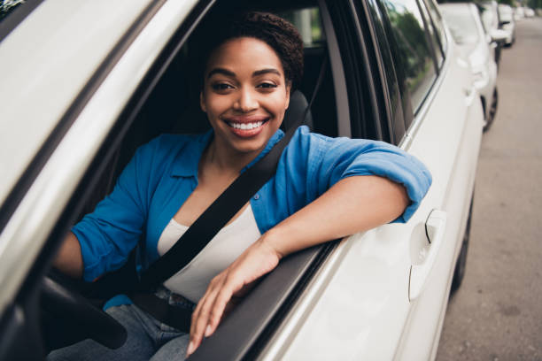 istock Young woman smiling confidently while driving a car on a sunny day 2194863184