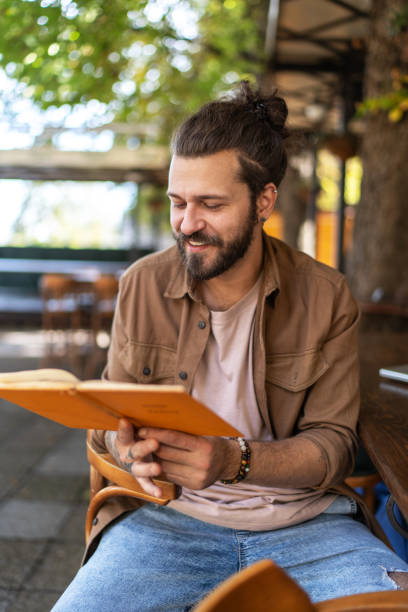 istock Handsome man reading a book at coffee shop 2194863255