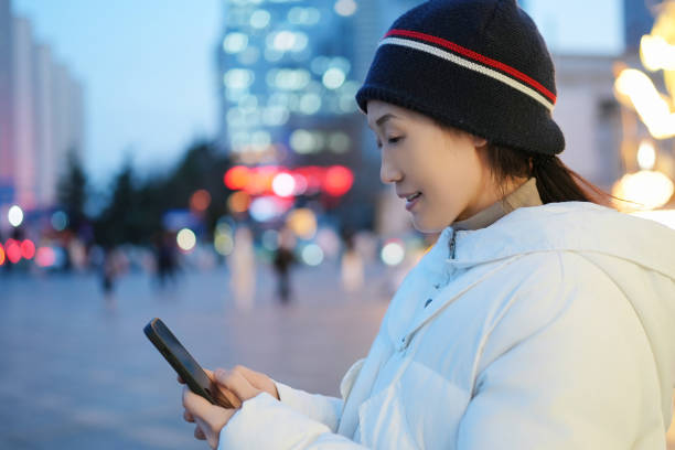 istock Young Woman Engaged with Smartphone in Urban Evening Setting 2194864262