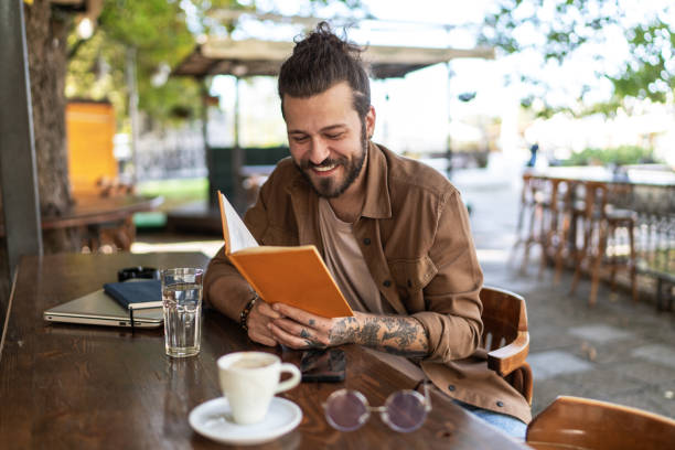 istock Handsome man reading book in outdoors cafe 2194867336