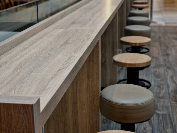 a row of circle-shaped bar chairs with leather upholstery and a glass partition, suede upholstered dining table chairs. wooden table and floor in the cafe, beige a row of circle-shaped bar chairs with leather upholstery and a glass partition, suede upholstered dining table chairs. wooden table and floor in the cafe, beige, laminate round wooden chair stock pictures, royalty-free photos & images