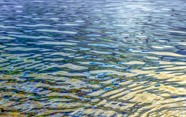 Rainbow colored surface of a calm sea, a wave rolling