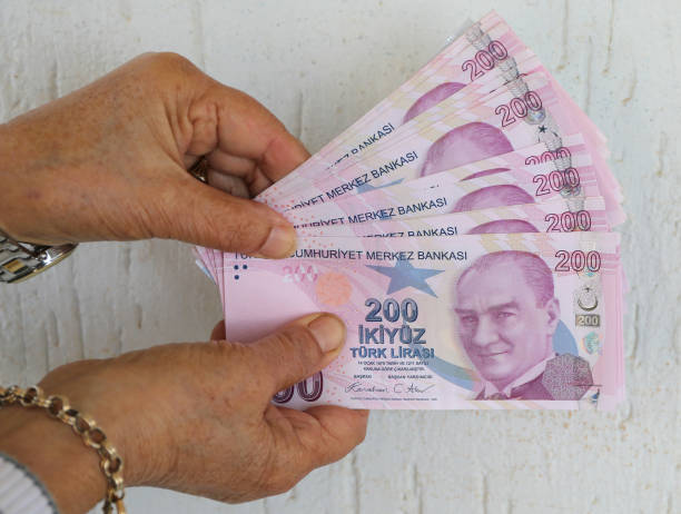 istock Hands Holding Turkish Lira Banknotes by White Wall 2194867658