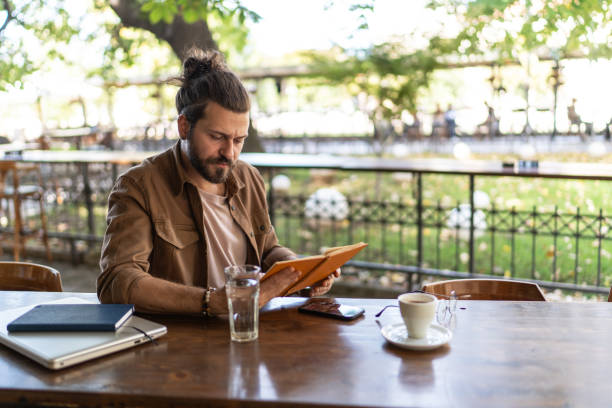 istock Handsome man reading book in outdoors cafe 2194867760