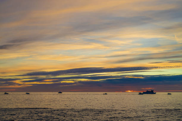 Colorful sunset landscape over the calm sea. Silhouettes of sea ships, yachts and boats against the evening twilight sky