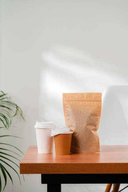Three beverage containers and a paper bag on a wooden table
