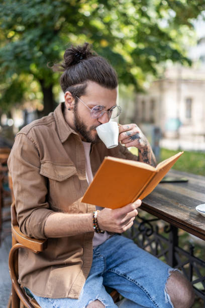 istock Handsome man drinking coffee and reading book in outdoors cafe 2194873795