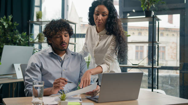 istock Arabian female leader coach help intern explain paperwork and financial data business strategy consult client. Smiling Indian colleague businessman talk with businesswoman corporate teamwork at office 2194874736