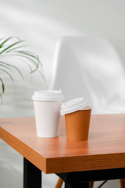 istock A disposable coffee cup on a wooden table beside a leafy plant 2194875557