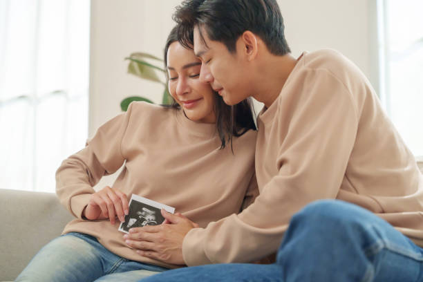 istock Asian Couple Enjoying a Cozy Moment While Looking at a Memory Book in Their Bright Living Room During the Daytime 2194875678