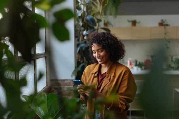 istock Young woman using smartphone in a plant-filled apartment 2194875718