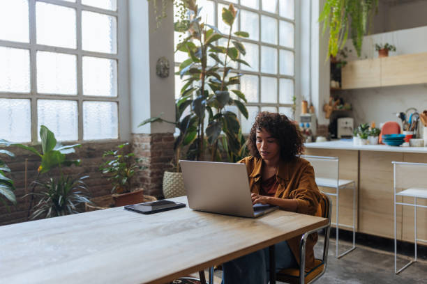 istock Young woman working from home using laptop in modern apartment 2194875733