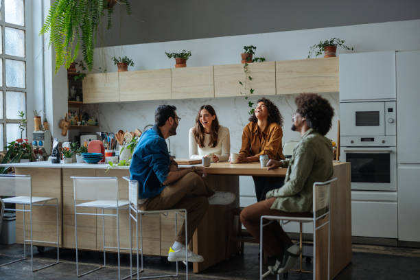 istock Four young adults chatting and laughing in modern kitchen 2194875762