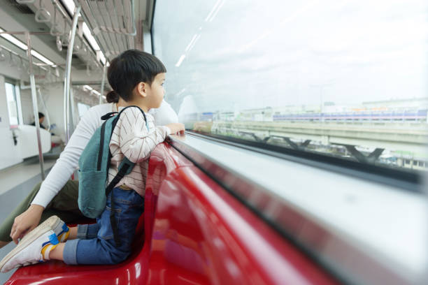 istock Asian child with a backpack looking out of a train window while traveling on an elevated public transit system. 2194875784