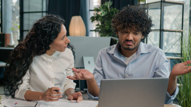 istock Annoyed woman business mentor teaching male intern help laptop work problem difficulties lazy man shrug shoulders. Multiethnic arabian businessman businesswoman talk misunderstanding office conflict 2194877012