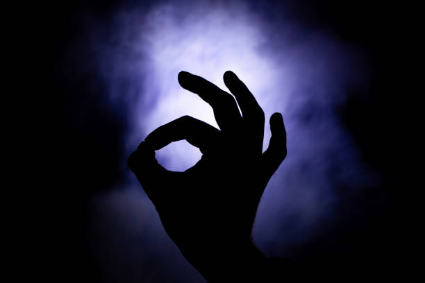 ok sign shown by hand in backlight on a smoky background