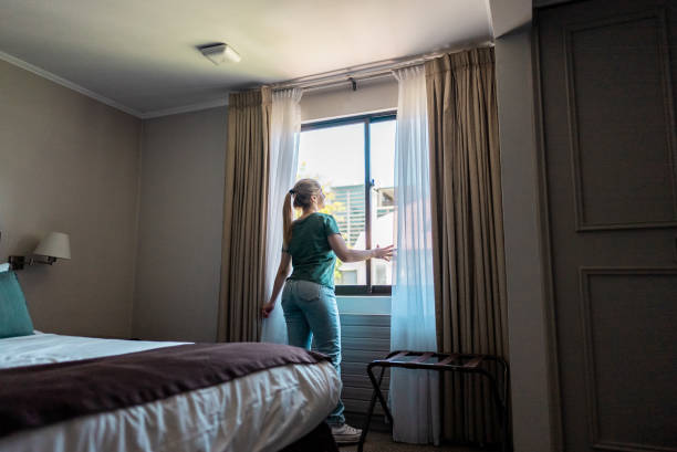 istock Young woman looking through window at hotel room 2194878774