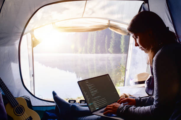 istock Young woman working on her laptop inside the tent during a camping vacation. 2194888992