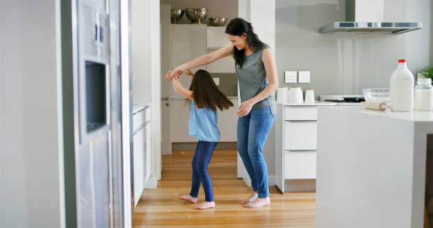 istock Mom, daughter and holding hands for dancing in home, love and support with learning movement. Mother, girl and teaching steps to child in kitchen, family fun and listening together to sound of music 2194889521