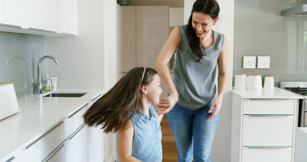 istock Mother, daughter and happy with dancing in kitchen for celebration, bonding and teaching steps. Energy, woman dancer and girl kid in home with moving together for weekend entertainment and spinning 2194889522