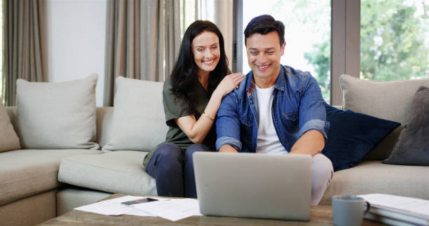 Sofa, couple and happy with laptop for finance, track expenses and success for budget goals at home. House, woman and man with technology for tax payment review, digital savings and mortgage bills Sofa, couple and happy with laptop for finance, track expenses and success for budget goals at home. House, woman and man with technology for tax payment review, digital savings and mortgage bills Young couple reviewing documents or smiling with a laptop stock pictures, royalty-free photos & images