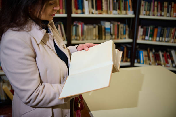 istock Woman examining a blank book in a detailed library setting 2194890375