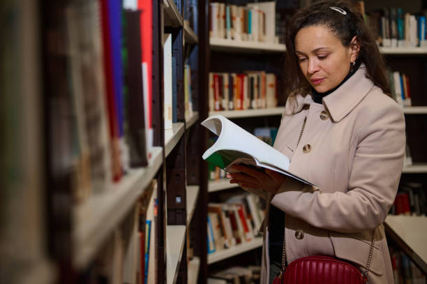 istock Woman reading a book in a library for World Book Day 2194890400