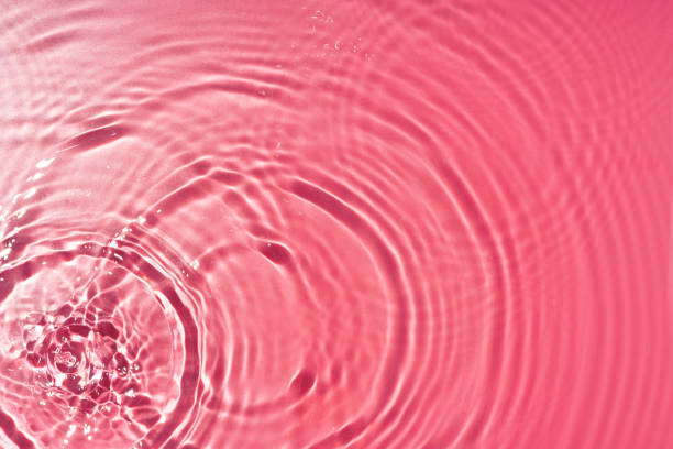 Ripples of light and color in a pink water surface reflecting mesmerizing patterns at midday top view