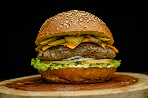 istock Artisan hamburger with white sauce, cheddar cheese, pickles, lettuce, onion and tomato on a wooden base. 2194895411