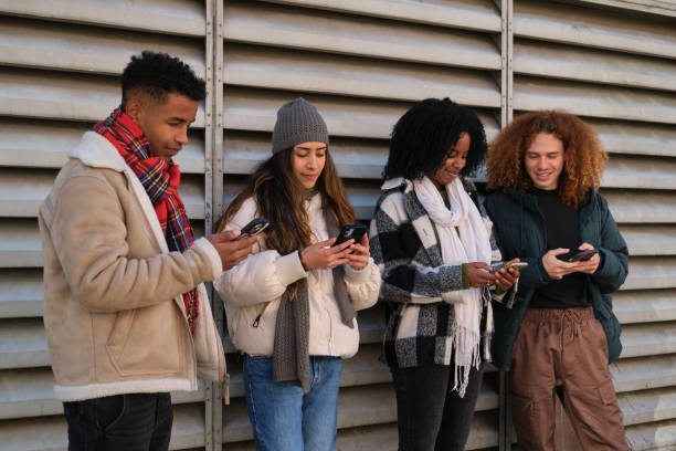 istock Young people using smartphones standing next to a wall 2194897118
