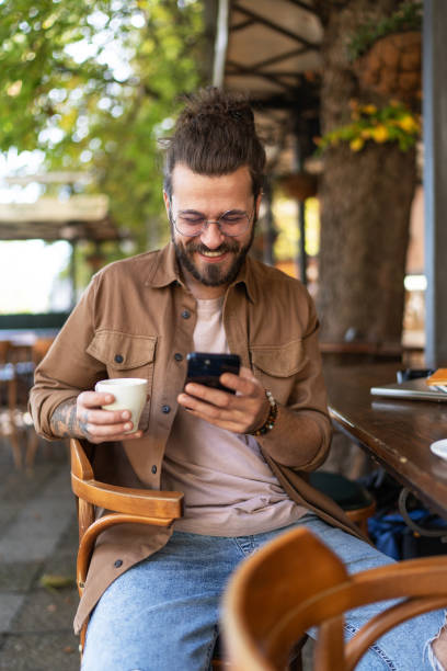 istock Young man drinking coffee and using phone in a sidewalk cafe 2194897307