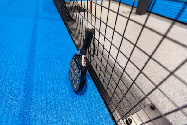 istock Black professional paddle tennis racket and ball with natural lighting on blue background. Horizontal sport theme poster, greeting cards, headers, website and app 2194899574