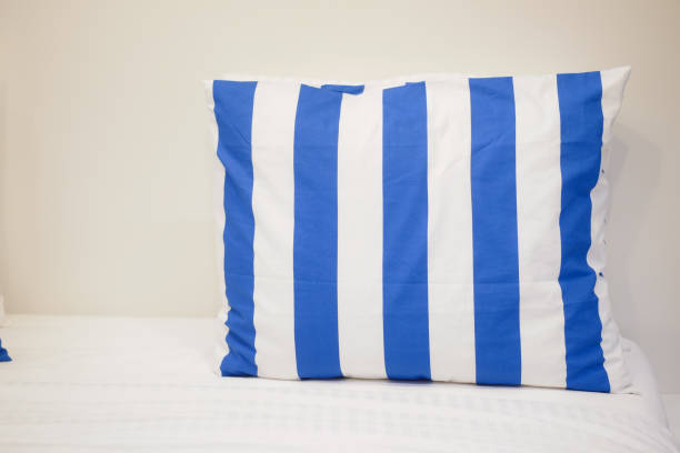 A stylish blue and white striped pillow is resting elegantly on a clean and crisp bed